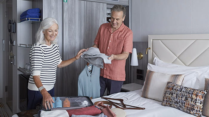A couple unpacking in a standard cabin aboard Spirit of Adventure